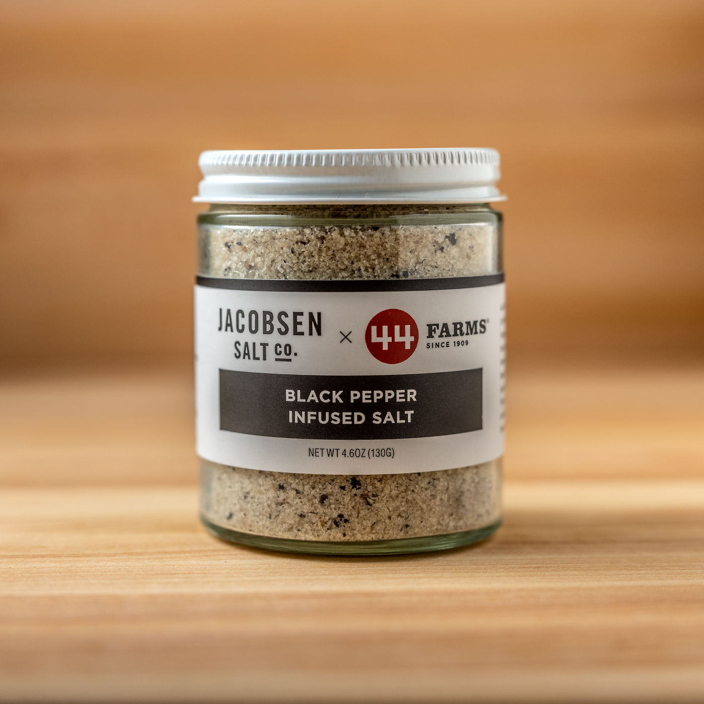 Jar of black pepper infused salt from Jacobsen Salt Co. on a wooden surface
